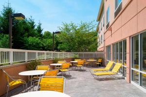 eine Terrasse mit gelben Stühlen und Tischen sowie ein Gebäude in der Unterkunft Fairfield Inn & Suites by Marriott State College in State College
