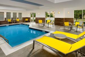 a pool with yellow chairs and tables in a hotel at Fairfield Inn & Suites Germantown Gaithersburg in Germantown