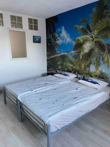 two beds in a room with a palm tree mural on the wall at Casa Brisa del mar in La Jaca