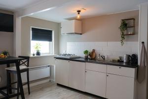 a kitchen with white cabinets and a sink at La Siesta Noordwijk Zee in Noordwijk