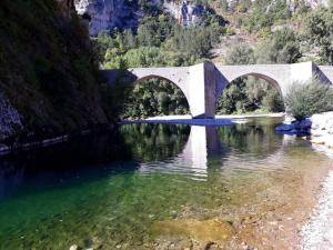 uma ponte sobre um rio ao lado de uma montanha em Ste ENIMIE GITE terrasse privative vue imprenable em Sainte-Enimie