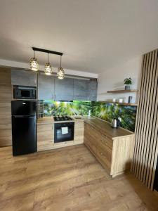 a kitchen with a black refrigerator and wooden cabinets at LUXURY GOLD APARTMENT by Marta in Radom