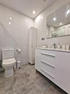 a white bathroom with a toilet and a sink at Hermoso Piso en La Cala de Mijas con vistas al mar in La Cala de Mijas