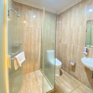 a bathroom with a shower and a toilet and a sink at Riverstone Hotel & Cottage in Batu