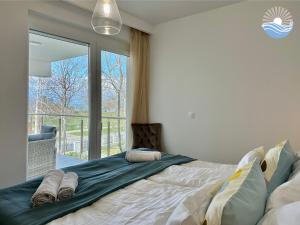een slaapkamer met een groot bed en een groot raam bij Sunshine Resort Blue Apartman in Zamárdi