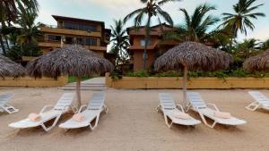 - un groupe de chaises longues et de parasols sur une plage dans l'établissement Park Royal Homestay Los Tules Puerto Vallarta, à Puerto Vallarta