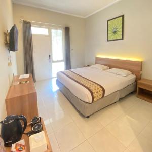 ein Schlafzimmer mit einem Bett und einem TV in der Unterkunft Riverstone Hotel & Cottage in Batu