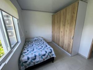 a small bedroom with a bed and a wooden cabinet at Sierra Verde Living Suites in Apartadó