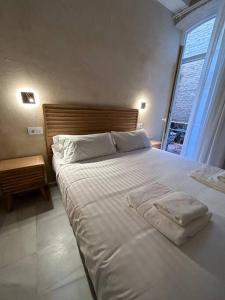 1 dormitorio con 1 cama blanca grande y ventana en Casa Procurador Triana, en Sevilla