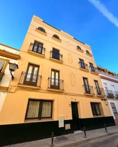 un edificio alto de color amarillo con ventanas en una calle en Casa Procurador Triana, en Sevilla