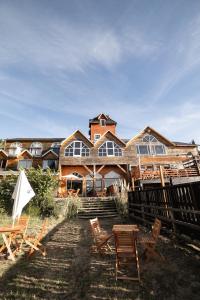 une grande maison en bois avec des chaises en face de celle-ci dans l'établissement Hosteria La Luna, à San Carlos de Bariloche