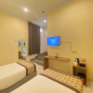 a hotel room with two beds and a flat screen tv at Riverstone Hotel & Cottage in Batu