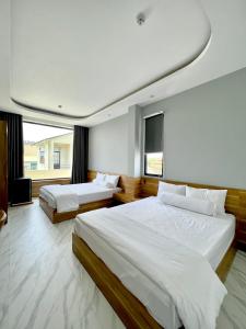 1 dormitorio con 2 camas y ventana grande en BITA HOTEL CẦN THƠ, en Bình Thủy