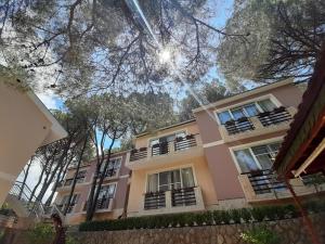 a pink building with balconies and trees at Hotel Art Media in Herceg-Novi