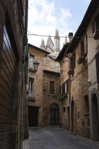 Une allée dans un ancien bâtiment en pierre avec une tour dans l'établissement Ad un passo dal Duomo, à Orvieto