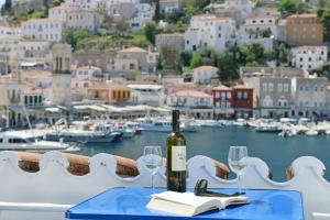 uma garrafa de vinho sentada numa mesa com copos de vinho em Delfini Hotel em Hydra