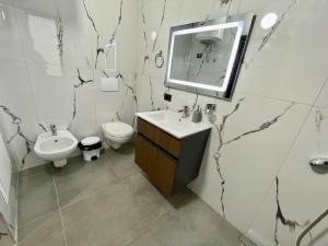 a bathroom with a sink and a toilet and a mirror at Keon superb studio apartament in Tirana