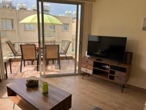 ein Wohnzimmer mit einem Flachbild-TV und einem Tisch in der Unterkunft Diamond Complex in Paphos City