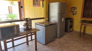 a kitchen with a refrigerator and a table with a tv at CASA AMARELA Beira Rio Guriri in Guriri