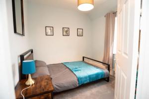 a bedroom with a bed and a table with a blue lamp at Sherwood Pines - Big Garden! in Clipstone