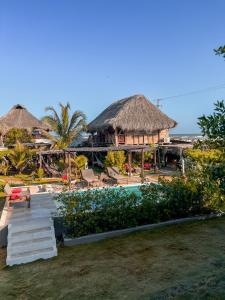 a resort with a pool and a building with thatched roofs at Kite Eco House in Salina de Rey