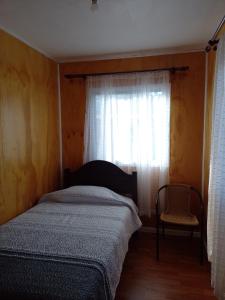 a bedroom with a bed and a window and a chair at Rita in Lota