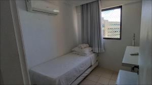 Habitación blanca pequeña con cama y ventana en Studio Portal dos Corais apartamento 1003, en Recife