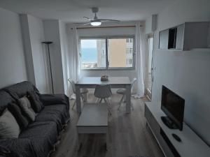 sala de estar con sofá, mesa y ventana en Precioso alojamiento junto al Mediterráneo, en La Manga del Mar Menor