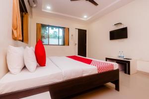 馬諾麗的住宿－OYO Manori Resort，一间卧室配有一张带红色枕头的大床