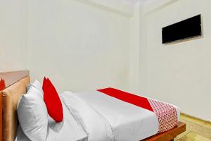 1 dormitorio con 1 cama con almohadas rojas y blancas en OYO Yash Hotel, en Ghaziabad