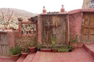 un bâtiment avec une porte en bois et des plantes en pot dans l'établissement Tigmino Maison D'or, à Tafraout