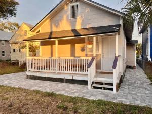 een geel huis met een veranda met een wit terras bij Lovely Guesthouse in the Up-and-Coming Springfield in Jacksonville