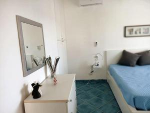 een slaapkamer met een bed en een tafel met een spiegel bij Casa dei Fiori in Donnalucata
