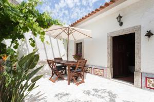 einen Tisch und Stühle mit Sonnenschirm auf einer Terrasse in der Unterkunft Mar e terra casa rústica in São Pedro da Cadeira