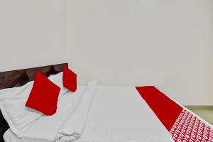 Una cama con almohadas rojas y blancas. en Collection O 45443 Hotel Suvidha, en Bilāspur