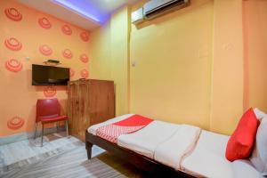 a bedroom with a bed and a chair and a tv at Super OYO Hotel Priyal Amrit Sagar in Rourkela