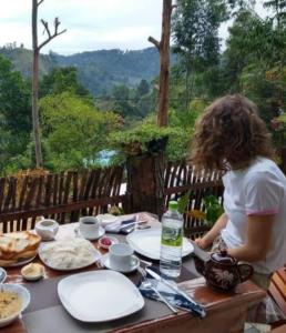 a woman sitting at a table with plates of food at Lazy Bear Lodge Ella in Ella
