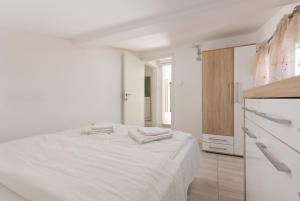 a white bedroom with a bed and a kitchen at Apartment Aleksic in Kotor