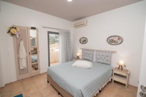 a white bedroom with a bed and a window at Tsaner Apartment and Rooms in Matala