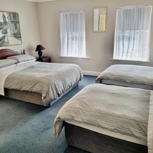 two beds in a bedroom with two windows at Dun Maeve Guesthouse in Westport
