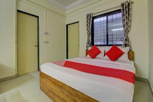 a bedroom with a bed with red pillows and a window at Flagship Sai Executive Lodging Near Fun Time Multiplex in Pune