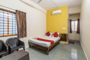 a bedroom with a bed and a chair in it at OYO Supriya Lodge in Hassan