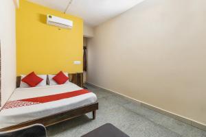 a bedroom with a bed and a yellow wall at OYO Supriya Lodge in Hassan