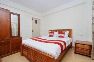 una camera da letto con un grande letto con cuscini rossi e bianchi di OYO Home Stay Fable Stay a Ooty