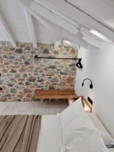 a bedroom with a brick wall with a bed and a bench at Stone build suite with private pool in Kolios