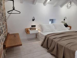 a white bedroom with a bed and a table at Stone build suite with private pool in Kolios