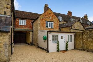 een garage met een witte garagedeur naast een gebouw bij Fox Cottage, within 5 min walk of Bicester Village in Bicester