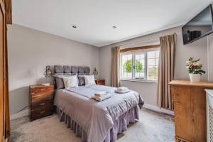 Un dormitorio con una cama grande y una ventana en Fox Cottage, within 5 min walk of Bicester Village, en Bicester
