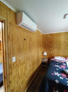 1 dormitorio con 1 cama y pared con paneles de madera en Departamento equipado Luisa, en Valdivia