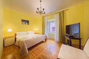 a yellow bedroom with a bed and a tv at Apartments Niko in Skradin